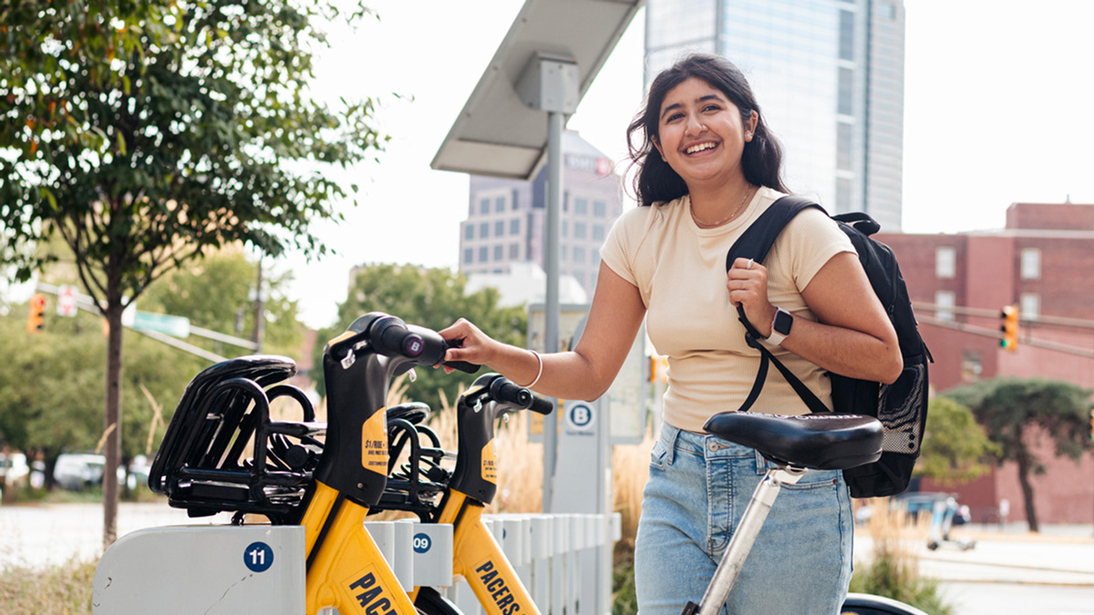 A student outside pictured with a bicycle.