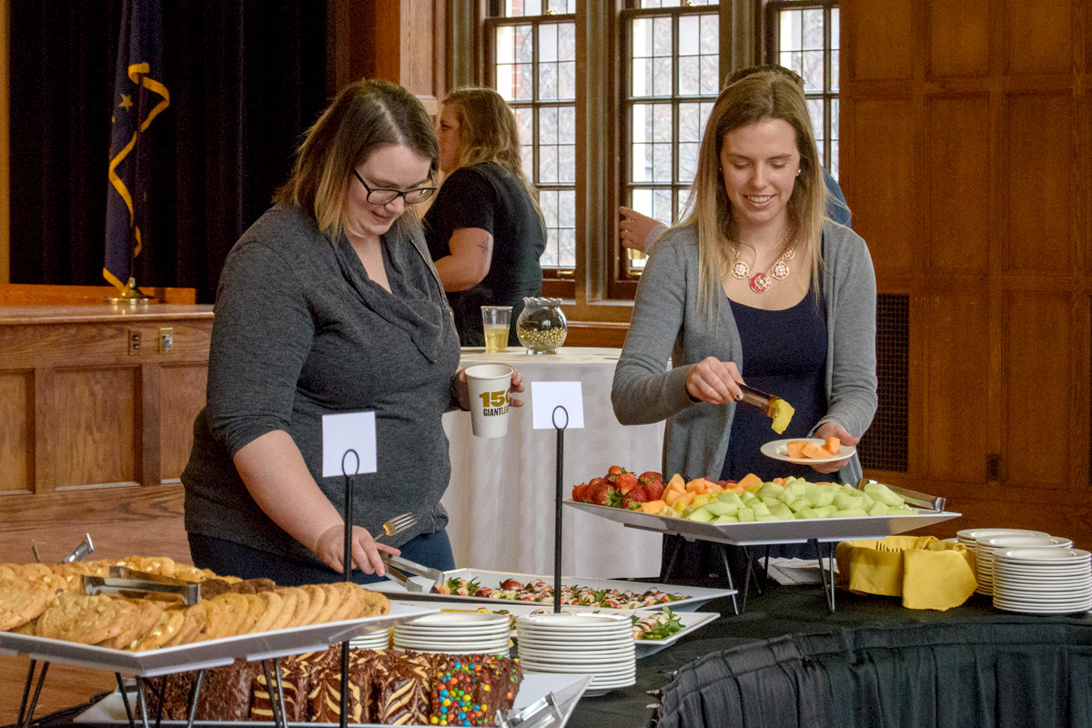 Attendees serving themselves at food banquet table during reception