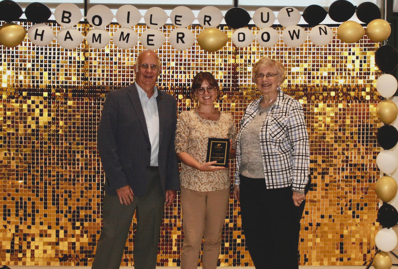 Genevieve Woodby with award and Bill and Barbara Rakosnik